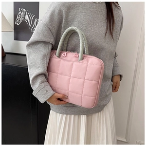 Detailed close-up of pink quilted laptop bag with durable green reinforced handles