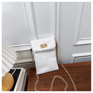 Detail of white plush phone bag with gold metal chain strap and twist-lock on wooden table