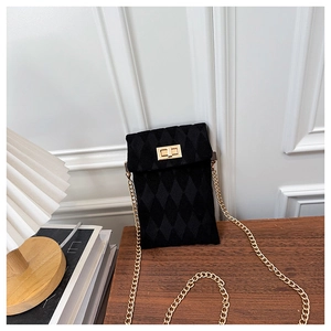 Detailed close-up of a black velvet quilted crossbody bag with gold chain and turn-lock