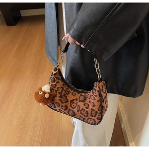 Detail of leopard print hobo bag with gold chain strap and brown fur ball pendant