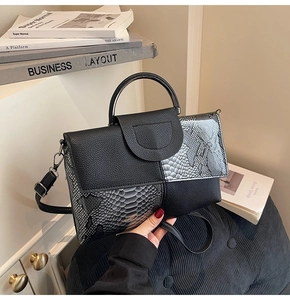 Detail showing mixed crocodile pattern leather and metallic ring handle on black handbag