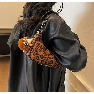 Detail of leopard print suede bag with gold chain strap and plush monster charm