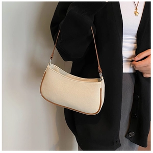 Detail van canvas en bruin lederen baguette tas gedragen als een crossbody tas