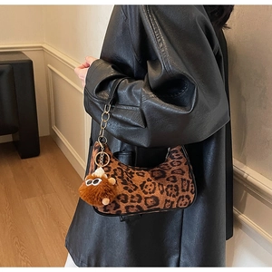Detail of leopard print suede shoulder bag with plush charm on a model in leather jacket