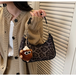 Detail of leopard print hobo bag with leather chain strap and cute plush charm pendant
