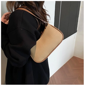 Detail van een bruine stoffen hobo-tas met lederen biezen, gedragen over de schouder voor dames