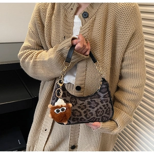 Detail of leopard print hobo bag with gold chain strap and plush pendant accessory