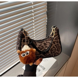 Detail of leopard print suede shoulder bag with gold chain and plush monster charm