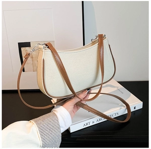 Detail van een vintage crème canvas handtas met bruine lederen bies vastgehouden