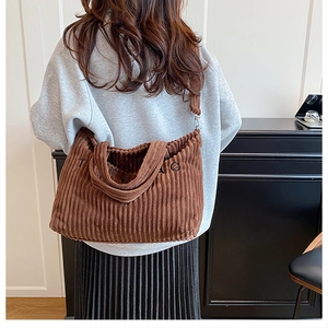Bruine corduroy draagtas met TOTE BAG borduursel getoond op een model voor de maat