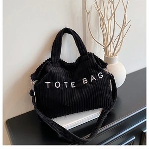 Detail van de zwarte corduroy draagtas met TOTE BAG tekst en verstelbare riem