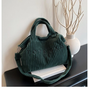 Detail van donkergroene corduroy draagtas met TOTE BAG borduursel en metalen onderdelen