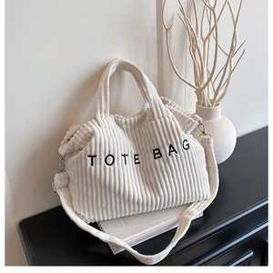 Detail van de ivoren corduroy draagtas met TOTE BAG borduursel en zachte textuurafwerking