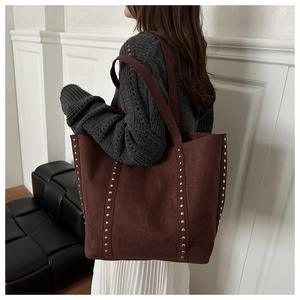 Detail of brown suede tote bag with silver rivets and long shoulder strap for women