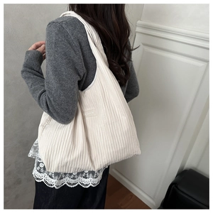 Close-up of beige pleated shoulder bag featuring a Fashion label on the side
