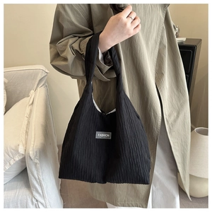 Macro detail of black pleated fabric texture and Fashion label on large tote bag