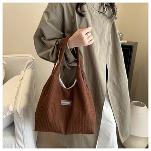 Detail der dunkelbraunen Plissee-Tasche mit Fashion-Label und strukturierter Puffer-Optik
