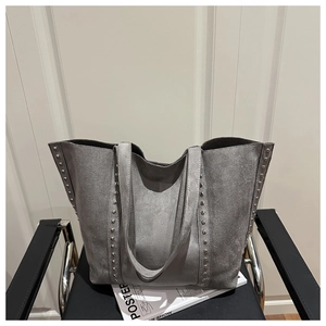 Detail of grey suede tote bag featuring silver rivet studs and spacious bucket design