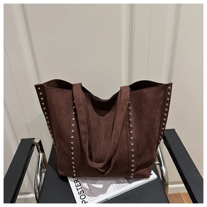 Detail of dark brown suede tote bag featuring silver rivet trim on the side straps