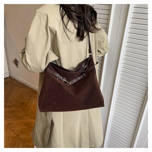 Model wearing dark brown suede tote bag with strap buckle detail on beige trench coat