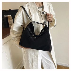 Detail of black suede tote bag showing its large capacity and leather strap with gold buckle
