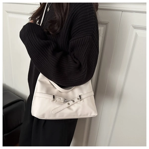 Detail of off-white leather underarm bag with decorative strap and silver metal buckle