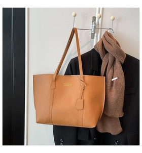 Brown leather tote bag styled with a black blazer and scarf for an autumn aesthetic
