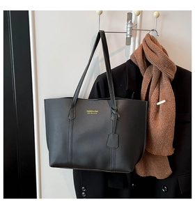 Detail of black tote bag with gold lettering hanging with a brown scarf and black blazer