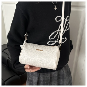 Detail view of a white quilted Boston barrel bag with gold fashion hardware on model