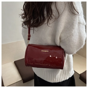 Detail van bordeauxrode laklederen Boston tas met goud logo en verstelbare schouderband