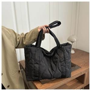 Detail of black quilted tote bag with wave stitching and wide shoulder straps