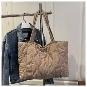 Quilted khaki tote bag hanging next to denim jacket showing large capacity and soft texture