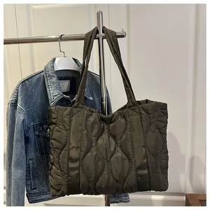 Detailed wave-quilted tote bag in olive green nylon hanging with casual denim jacket