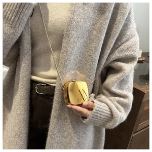 Detail of a mini golden metallic chain bag featuring a sleek mirror-like reflective finish