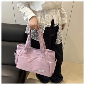 Detail einer helllilafarbenen Nylon-Tragetasche mit praktischen Taschen und Modelabel