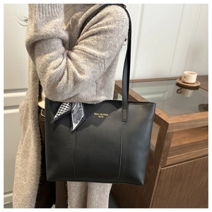 Minimalist black tote bag with geometric silk scarf detail on model in a modern interior