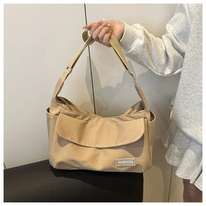 Vue détaillée du sac bandoulière en nylon beige avec étiquette mode et poches latérales