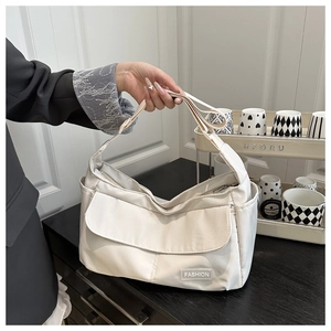 Détail d'un sac bandoulière en nylon crème avec étiquette mode et large sangle d'épaule