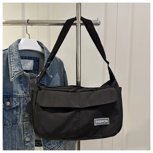 Détail du sac bandoulière en nylon noir avec étiquette 'FASHION' et sangle