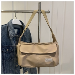 Détail du sac bandoulière en nylon kaki avec large sangle et étiquette de mode devant