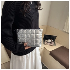 Close-up of silver quilted puffy makeup bag with metallic finish and top zipper detail