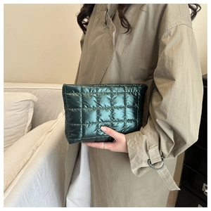 Dark green quilted handbag held by a model in a trench coat, minimalist fashion style