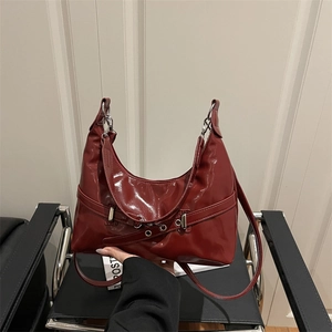 Glossy dark red underarm bag with metal eyelets and silver buckle in retro style