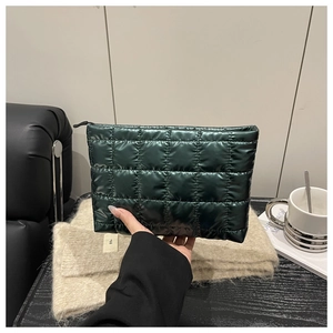 Detail of dark green quilted makeup bag with metallic finish and black zipper closure