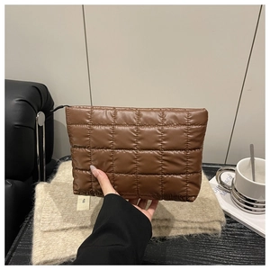 Detailed view of a brown quilted puffer clutch bag featuring smooth black zipper closure