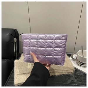 Handheld view of purple quilted cosmetic bag with metallic finish and black zipper