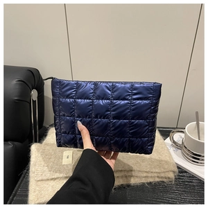 Detail of navy blue quilted puffer pouch bag held in hand for daily makeup storage