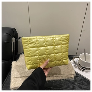 Detail of bright yellow quilted makeup bag with satin finish and black zipper closure