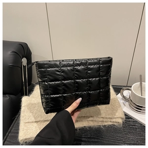 Close-up of black quilted puff clutch bag with sleek zipper and soft texture