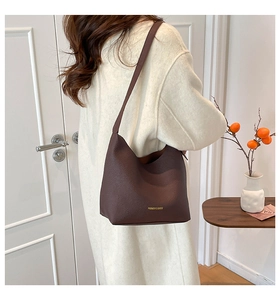 Detail of dark brown pebble leather shoulder bag with gold embossed brand logo